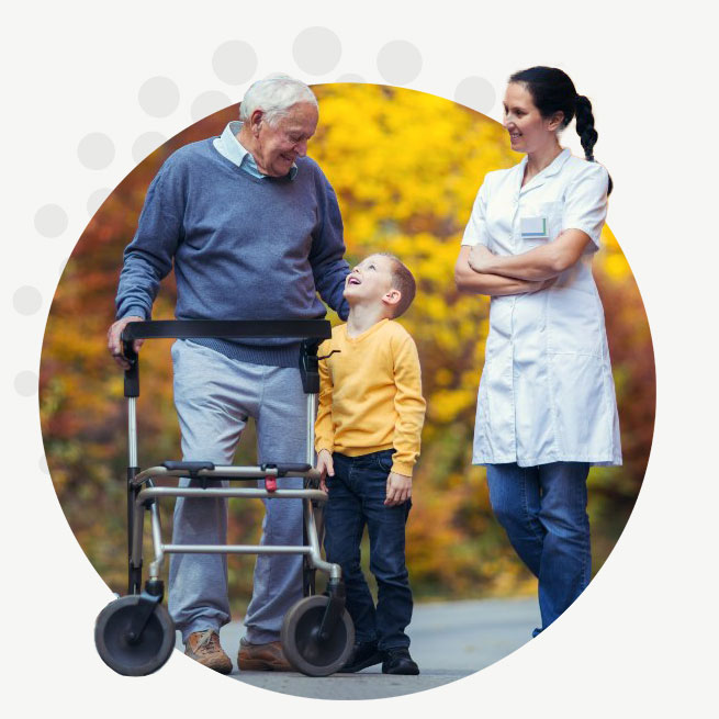 CHPCA-CIRCLE-Hike-For-Hospice An elderly man with a walker walking with a young boy and a female nurse outside in the fall.
