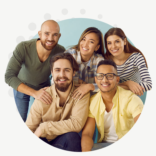 A group of young people smiling at the person taking their picture.