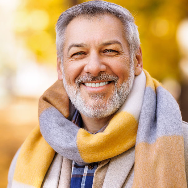 A middle aged man with a beard wearing a woolen scarf around his neck.